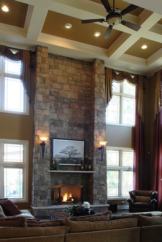 На фото: гостиная комната в классическом стиле с темным паркетным полом, стандартным камином, фасадом камина из камня, коричневым полом и кессонным потолком
