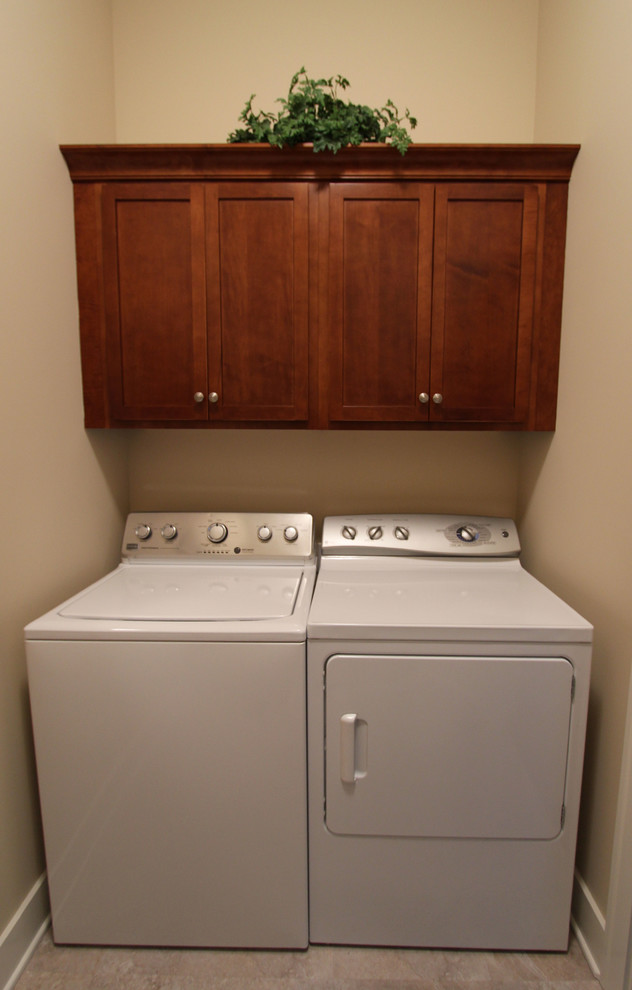 Design ideas for a small transitional single-wall laundry cupboard in Grand Rapids with recessed-panel cabinets, quartz benchtops, multi-coloured splashback, a drop-in sink, dark wood cabinets, beige walls, linoleum floors and a side-by-side washer and dryer.