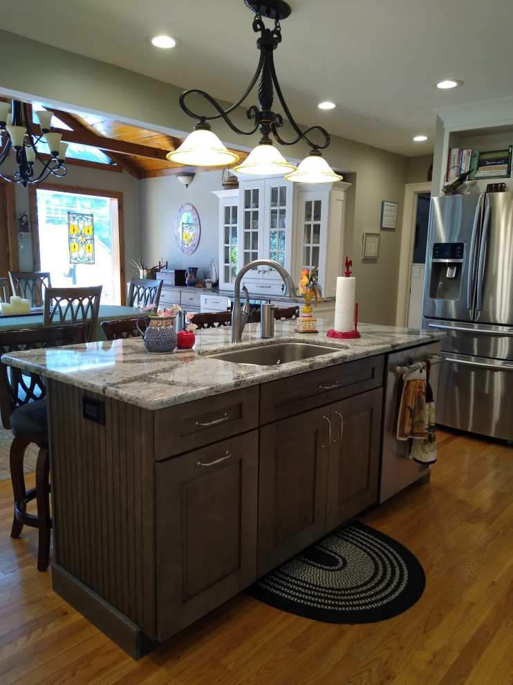 Exempel på ett mellanstort klassiskt grå grått kök, med en undermonterad diskho, luckor med upphöjd panel, skåp i mörkt trä, bänkskiva i kvarts, grått stänkskydd, stänkskydd i porslinskakel, rostfria vitvaror, mellanmörkt trägolv, en köksö och orange golv
