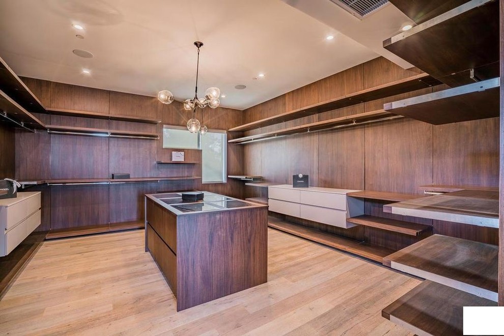 This is an example of a large modern men's walk-in wardrobe in Los Angeles with open cabinets, medium wood cabinets, bamboo floors and beige floor.