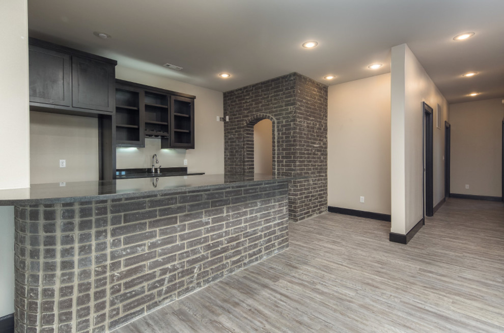 Large transitional u-shaped medium tone wood floor and brown floor home design photo with an undermount sink, shaker cabinets, black cabinets and granite countertops