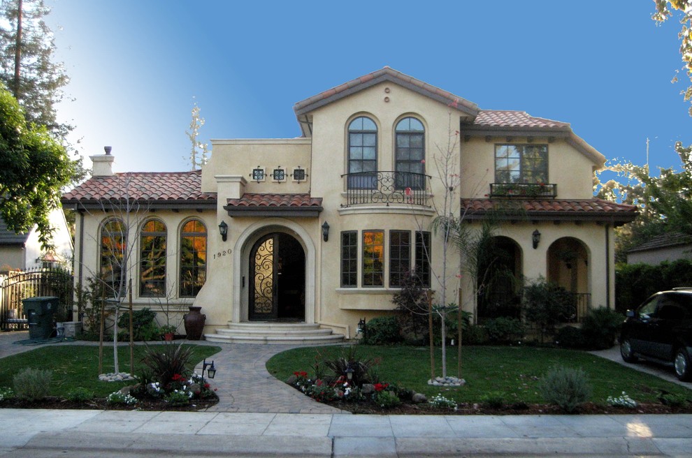 Inspiration for a large mediterranean two-storey stucco beige house exterior in San Francisco with a gable roof, a tile roof and a red roof.