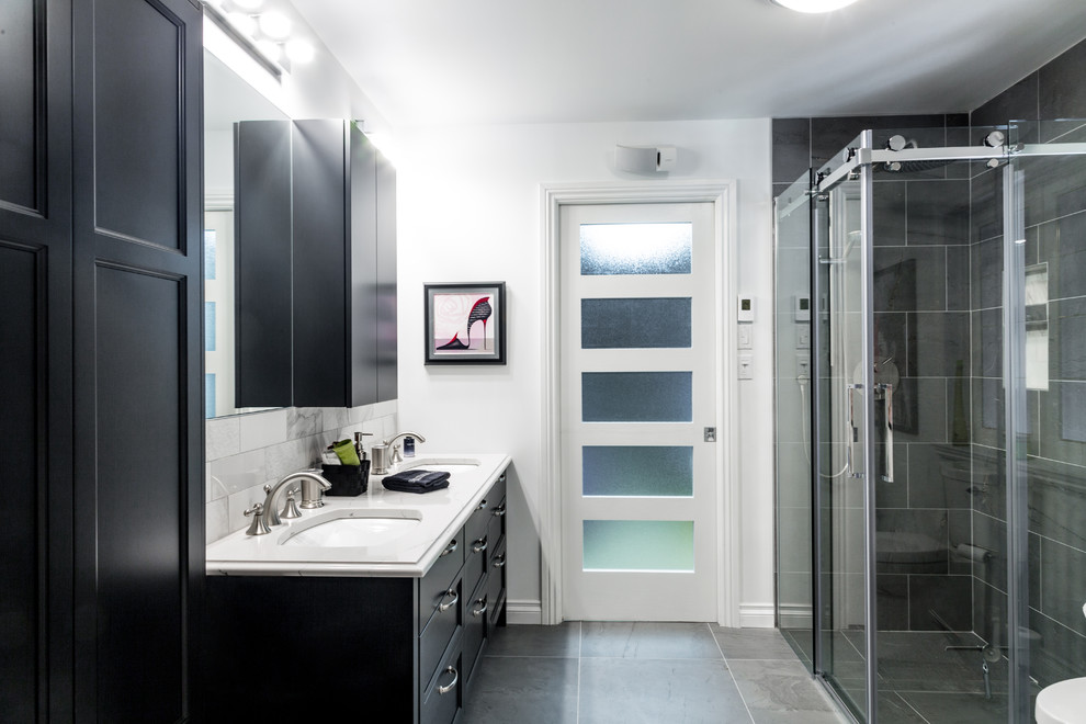 Photo of a mid-sized contemporary master bathroom in Montreal with shaker cabinets, grey cabinets, a freestanding tub, a corner shower, a two-piece toilet, gray tile, porcelain tile, white walls, porcelain floors, an undermount sink, engineered quartz benchtops, grey floor and a sliding shower screen.