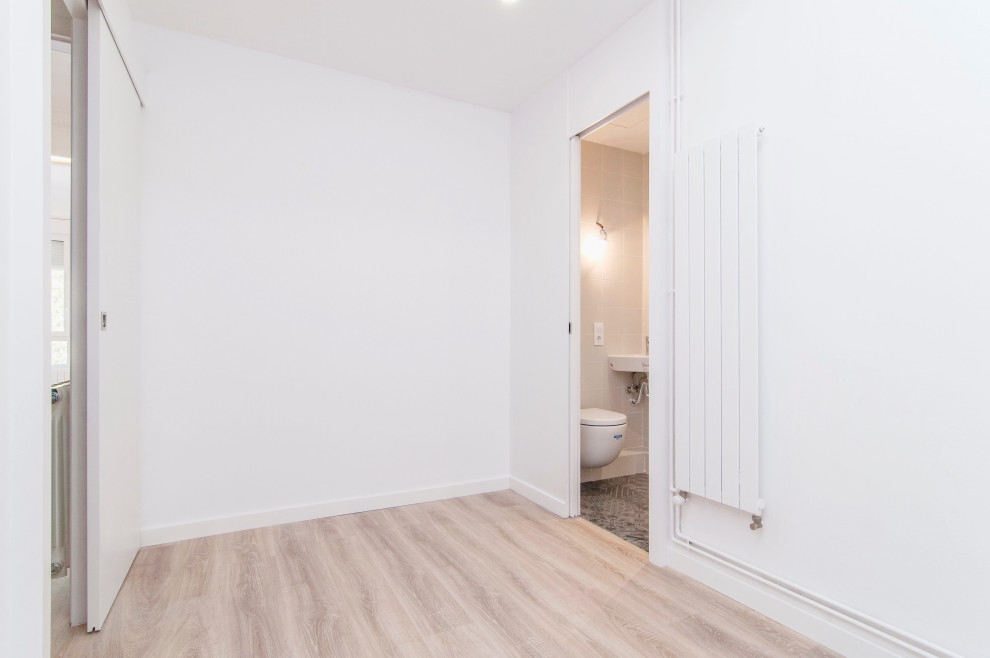 Foto di una camera matrimoniale classica di medie dimensioni con pareti bianche, pavimento in laminato e pavimento marrone