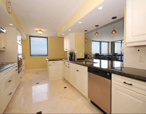 Inspiration for a transitional galley travertine floor open concept kitchen remodel in Miami with an undermount sink, raised-panel cabinets, white cabinets, white backsplash, ceramic backsplash and stainless steel appliances