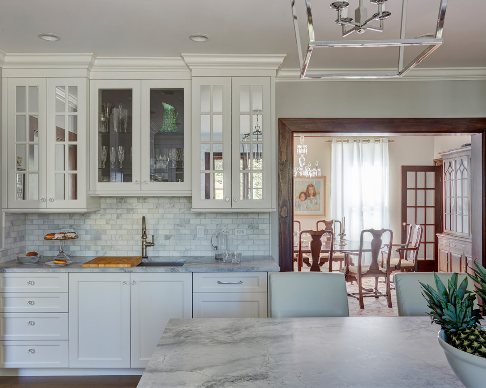 Inspiration for a large traditional u-shaped separate kitchen in Chicago with an undermount sink, shaker cabinets, white cabinets, marble benchtops, white splashback, marble splashback, stainless steel appliances, medium hardwood floors, with island and brown floor.