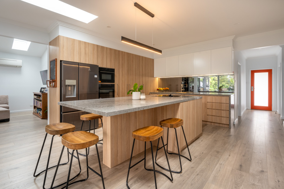 Photo of an expansive contemporary eat-in kitchen in Wollongong with a double-bowl sink, shaker cabinets, white cabinets, quartz benchtops, black splashback, mirror splashback, stainless steel appliances, light hardwood floors, with island and multi-coloured benchtop.