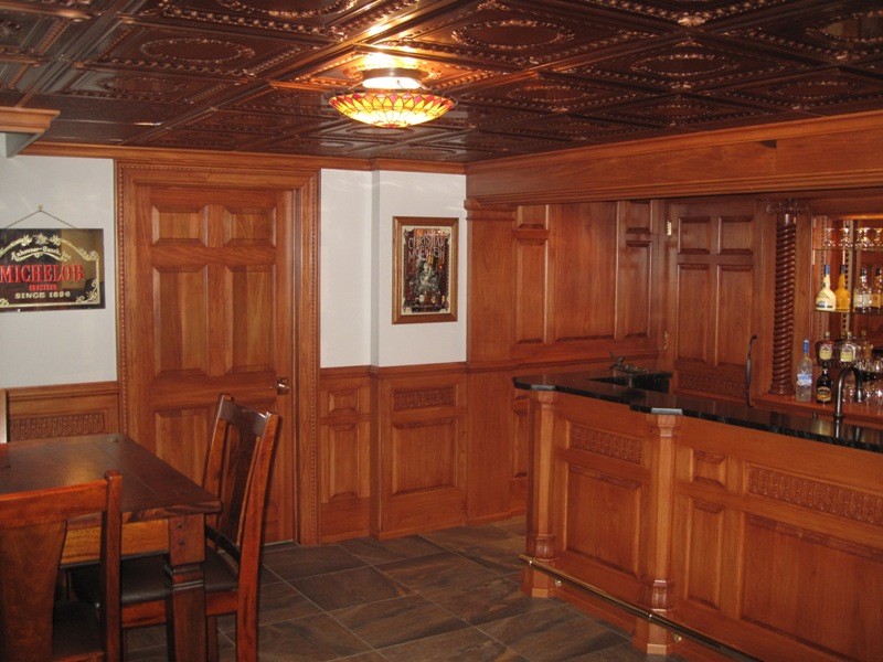 This is an example of a traditional u-shaped wet bar in Other with raised-panel cabinets, medium wood cabinets, granite benchtops and slate floors.