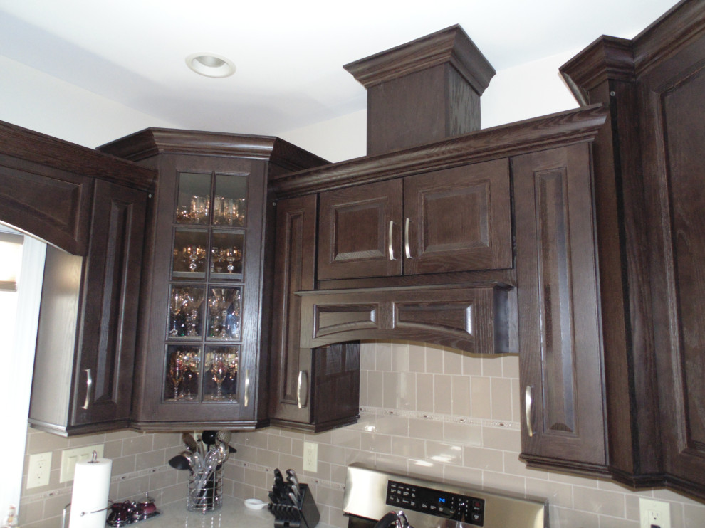 Example of a mid-sized transitional u-shaped ceramic tile and beige floor kitchen design with an undermount sink, raised-panel cabinets, dark wood cabinets, quartz countertops, beige backsplash, subway tile backsplash, stainless steel appliances and beige countertops