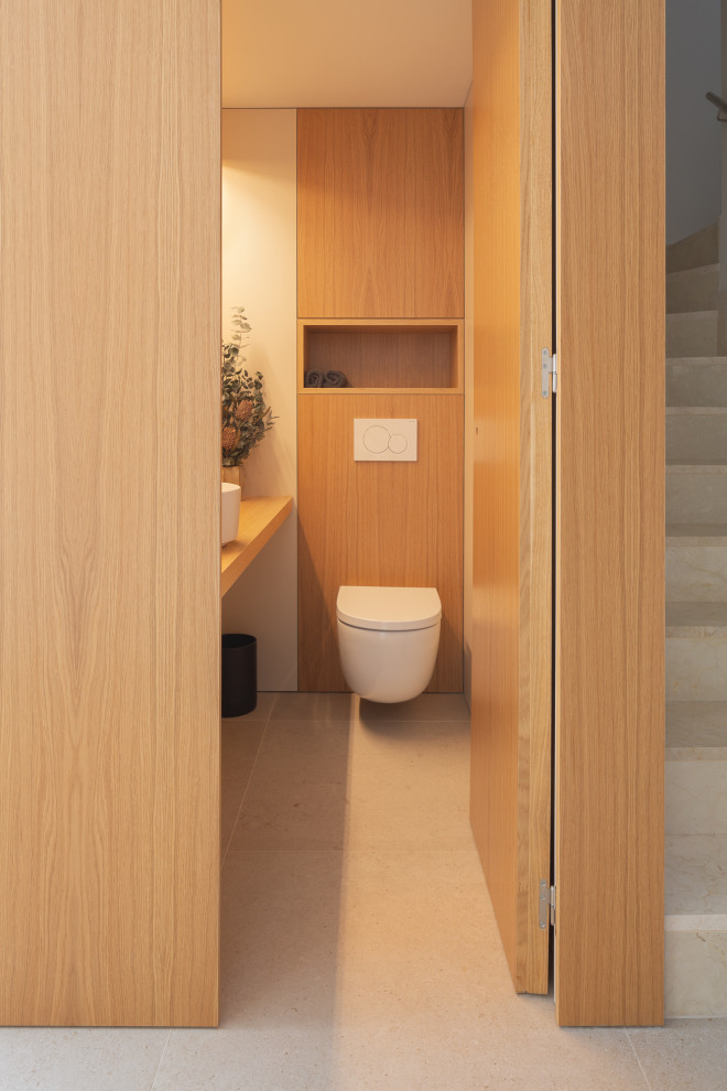 Foto på ett litet nordiskt brun toalett, med vita skåp, klinkergolv i porslin, ett fristående handfat, träbänkskiva och beiget golv
