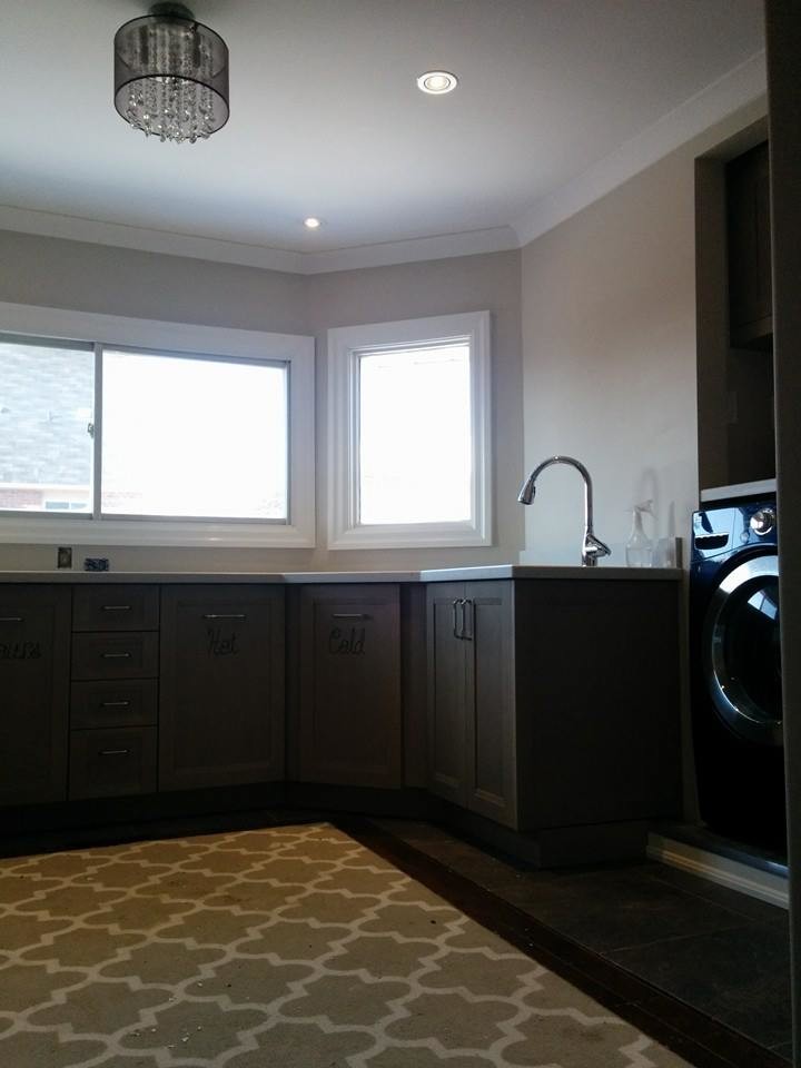Large transitional u-shaped slate floor dedicated laundry room photo in Toronto with an undermount sink, shaker cabinets, gray cabinets, limestone countertops, beige walls and a side-by-side washer/dryer