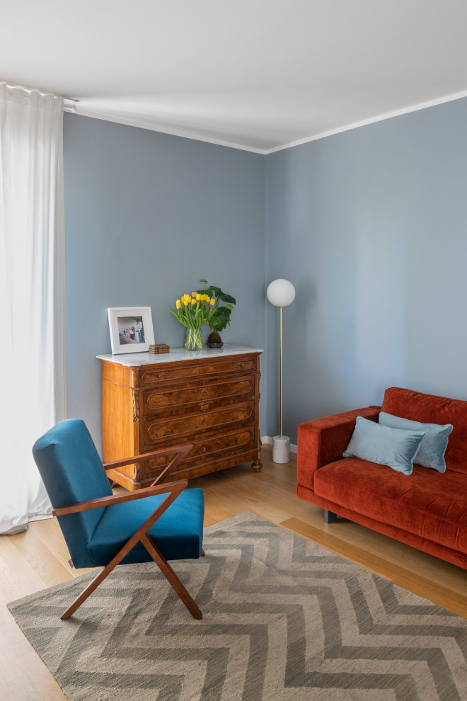Immagine di un ampio soggiorno moderno aperto con libreria, pareti blu, parquet chiaro, TV a parete e con abbinamento di mobili antichi e moderni