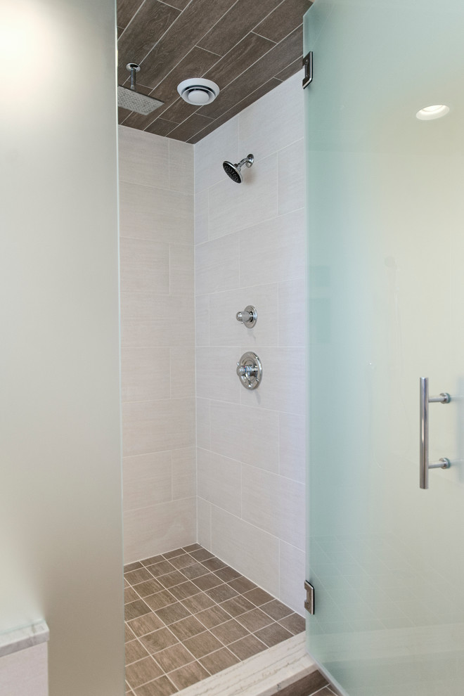 Example of a transitional beige tile and ceramic tile freestanding bathtub design with an undermount sink, raised-panel cabinets, white cabinets, marble countertops and a two-piece toilet