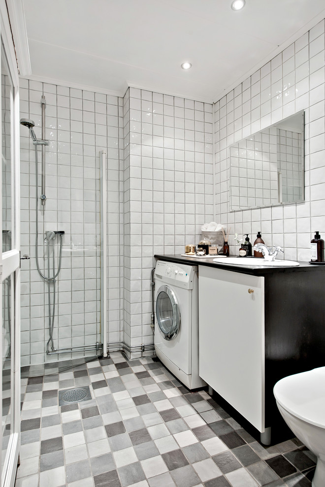 Photo of a mid-sized scandinavian 3/4 bathroom in Gothenburg with flat-panel cabinets, white cabinets, a corner shower, porcelain tile, grey floor, white tile, a drop-in sink, an open shower and a laundry.