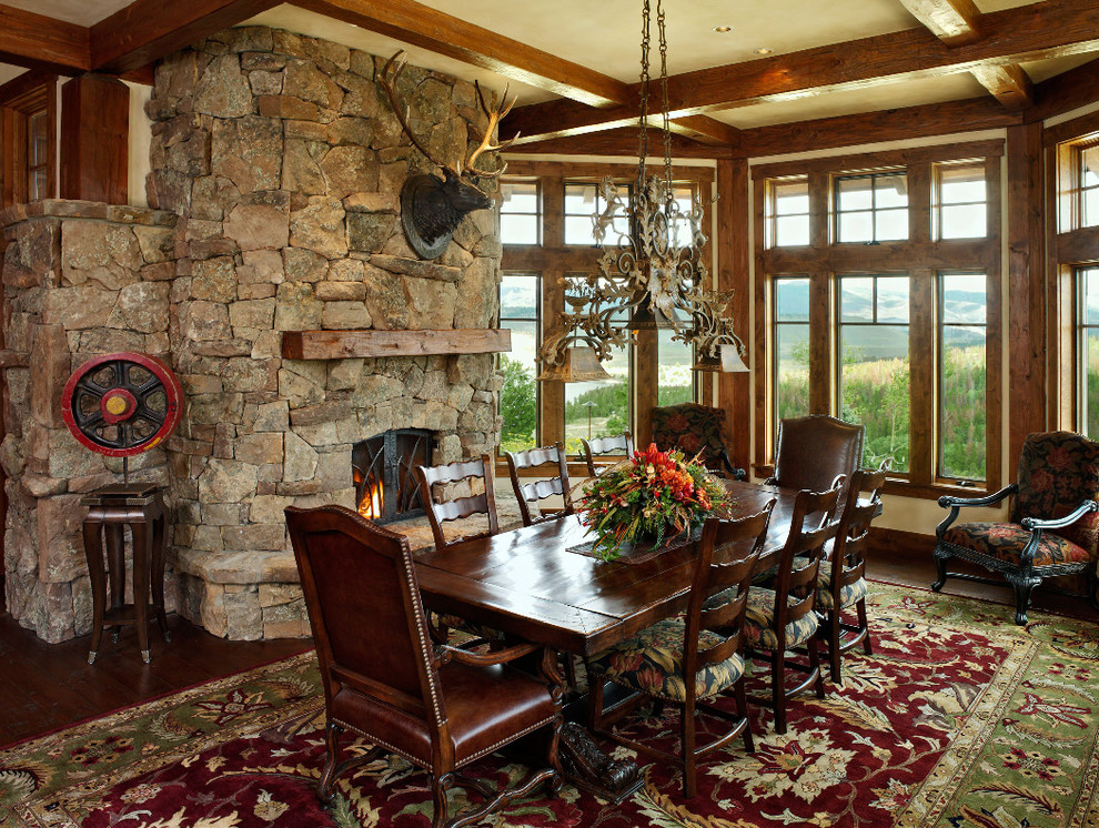 Photo of a country dining room in Denver with a stone fireplace surround.