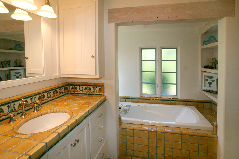 This is an example of a mediterranean master bathroom in San Francisco with an undermount sink, beaded inset cabinets, white cabinets, tile benchtops, a drop-in tub, yellow tile, ceramic tile and white walls.