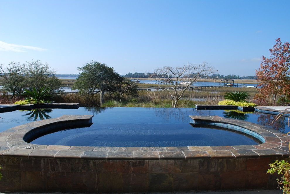 Example of a large backyard tile and custom-shaped infinity hot tub design