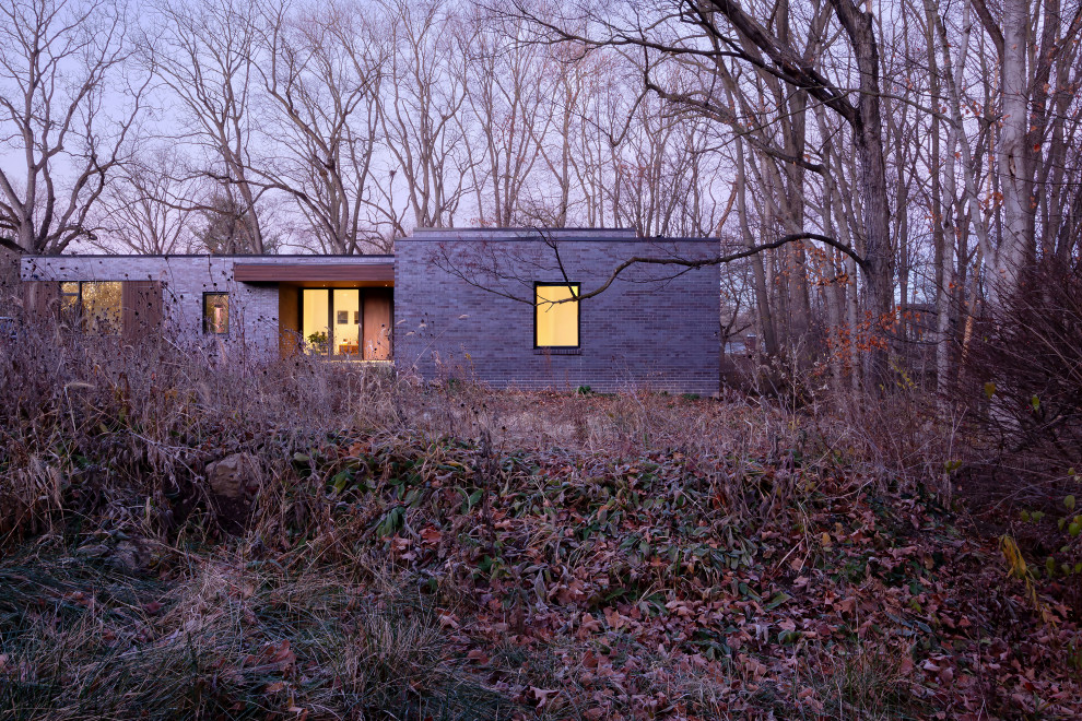 Aménagement d'une façade de maison multicolore moderne en brique de plain-pied avec un toit plat et un toit noir.