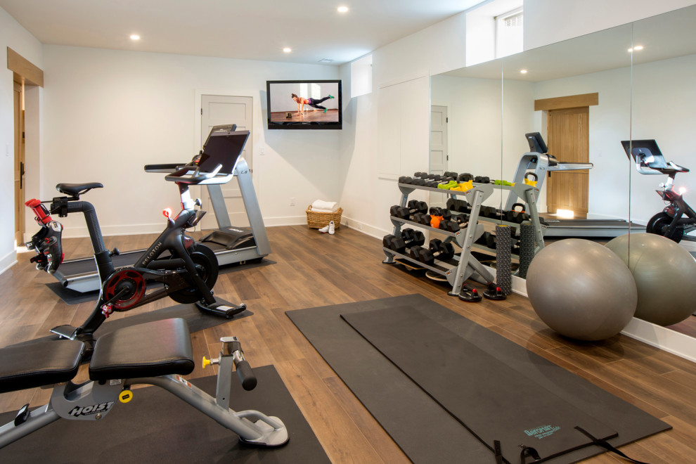 This is an example of a large contemporary multipurpose gym in New York with white walls, medium hardwood floors and brown floor.