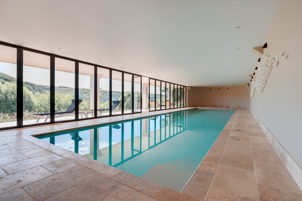 This is an example of a beach style rectangular pool in Devon with a pool house.