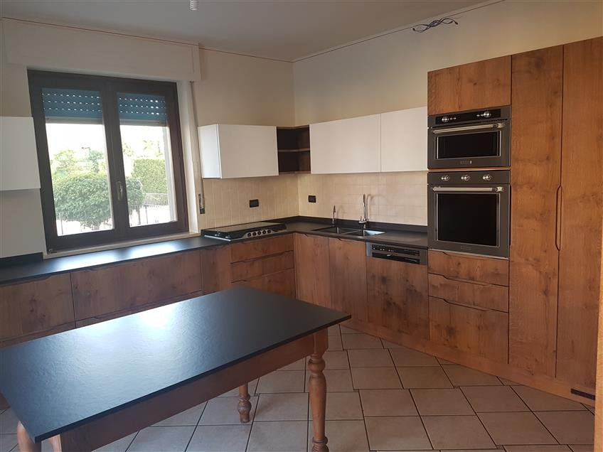 This is an example of a large rustic l-shaped kitchen/diner in Turin with a built-in sink, granite worktops, stainless steel appliances, terracotta flooring, beige floors and black worktops.
