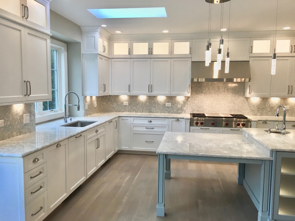 Large transitional u-shaped eat-in kitchen in Chicago with an undermount sink, shaker cabinets, white cabinets, quartz benchtops, panelled appliances, light hardwood floors, with island and grey floor.