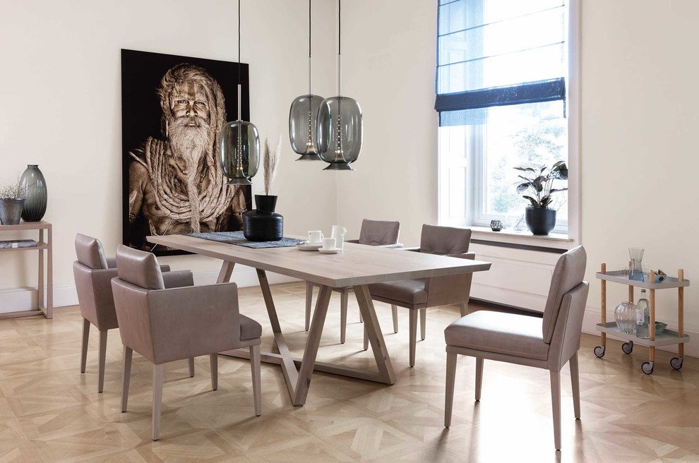 This is an example of a mid-sized contemporary separate dining room in Munich with white walls, light hardwood floors, no fireplace and beige floor.
