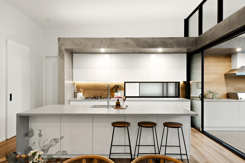 Esempio di una cucina design con lavello sottopiano, ante lisce, ante bianche, paraspruzzi marrone, paraspruzzi in legno, parquet chiaro, pavimento beige e top grigio