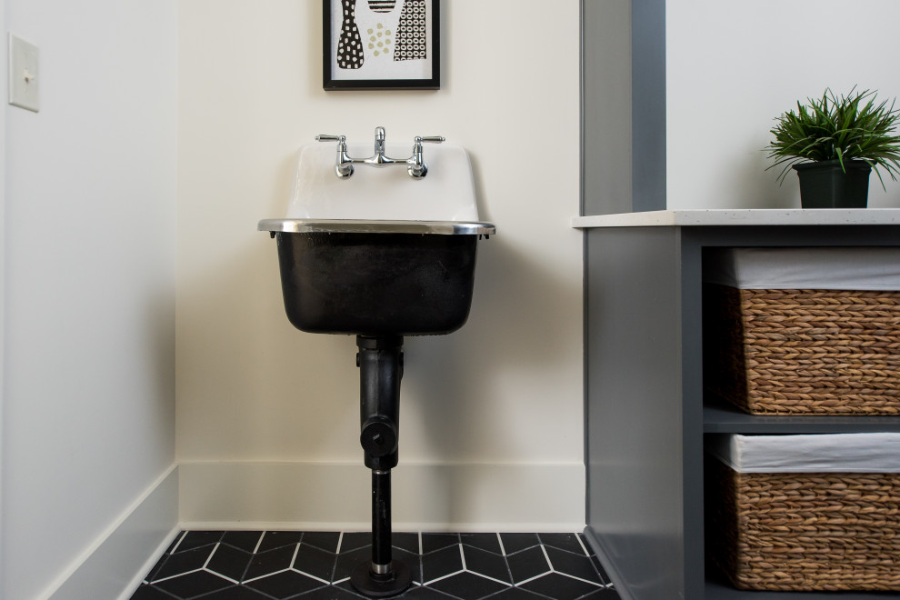 Example of a mid-sized minimalist u-shaped black floor dedicated laundry room design in Indianapolis with a drop-in sink, flat-panel cabinets, blue cabinets, quartz countertops, a side-by-side washer/dryer and white countertops