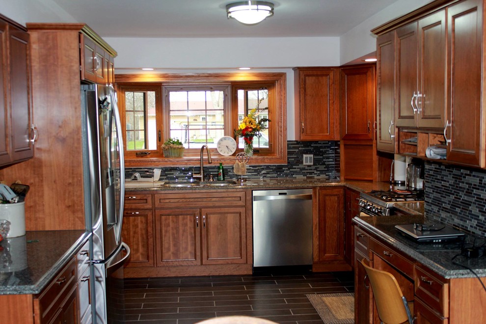 Example of a mid-sized transitional u-shaped enclosed kitchen design with an undermount sink, recessed-panel cabinets, medium tone wood cabinets, granite countertops, blue backsplash and glass tile backsplash