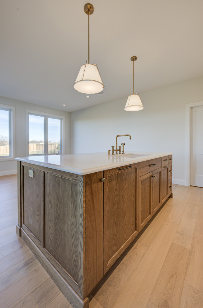 Mid-sized transitional single-wall light wood floor open concept kitchen photo in Toronto with an undermount sink, shaker cabinets, medium tone wood cabinets, quartz countertops, white backsplash, quartz backsplash, stainless steel appliances, an island and white countertops