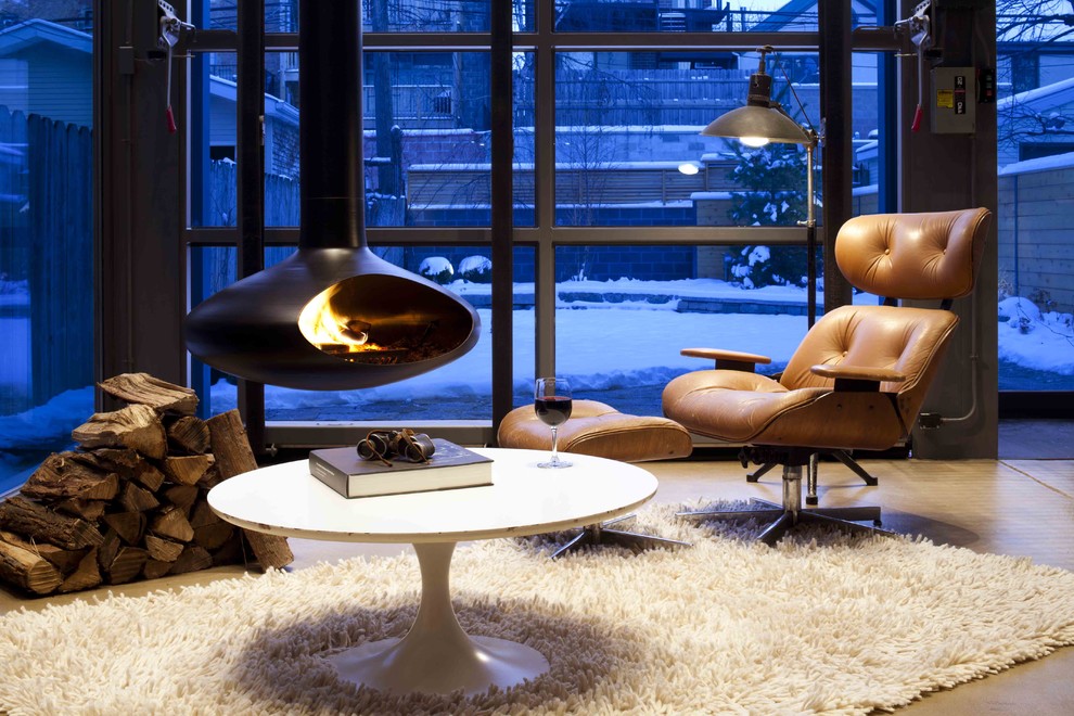 Photo of a small contemporary enclosed family room in Chicago with concrete floors and a hanging fireplace.