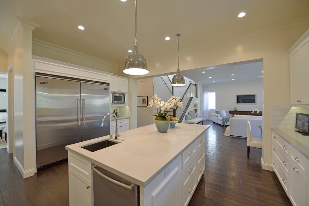 Large transitional u-shaped dark wood floor and brown floor eat-in kitchen photo in Los Angeles with an undermount sink, recessed-panel cabinets, white cabinets, granite countertops, white backsplash, ceramic backsplash, stainless steel appliances and an island