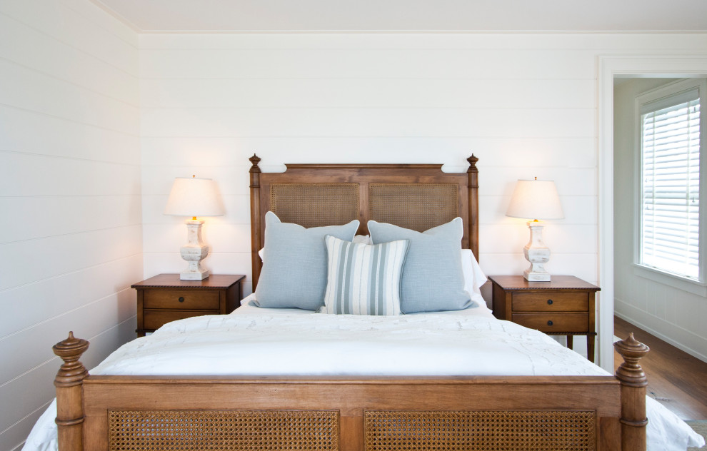 Ejemplo de habitación de invitados costera grande sin chimenea con paredes blancas, suelo de madera en tonos medios y suelo marrón