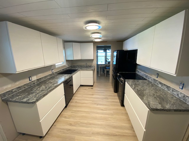 Inspiration for a small galley enclosed kitchen remodel with a double-bowl sink, laminate countertops, black appliances, no island and black countertops