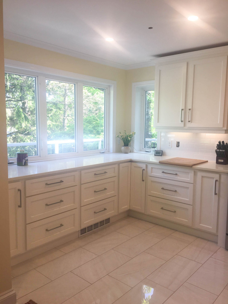 Example of a mid-sized transitional u-shaped porcelain tile and gray floor eat-in kitchen design with an undermount sink, shaker cabinets, white cabinets, quartz countertops, white backsplash, subway tile backsplash, stainless steel appliances, a peninsula and beige countertops