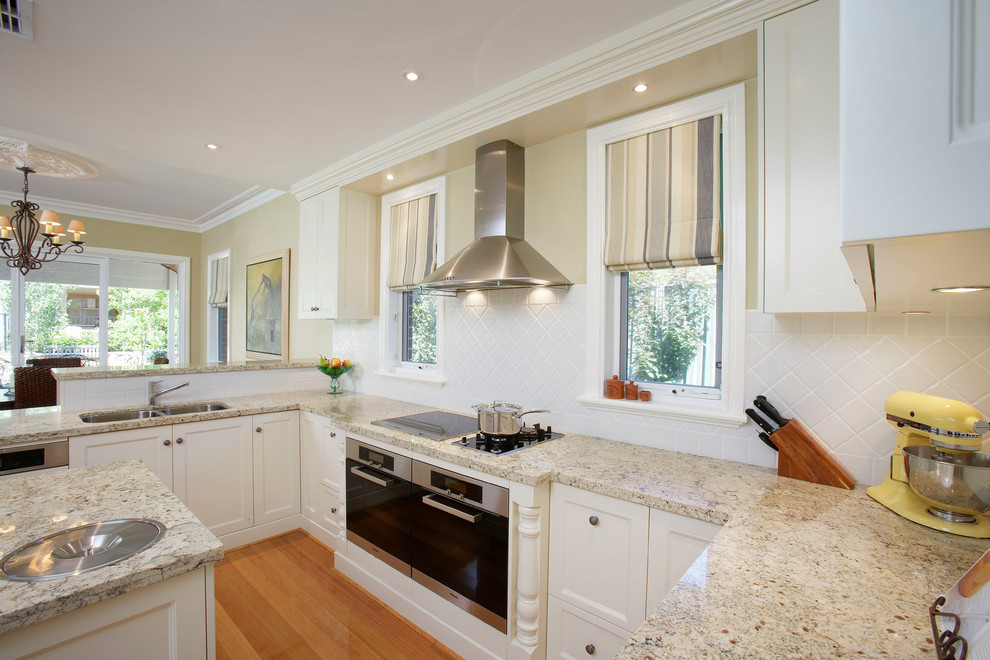 Photo of a traditional kitchen in Perth with shaker cabinets, white cabinets, granite benchtops, white splashback, porcelain splashback, stainless steel appliances, with island and multi-coloured benchtop.