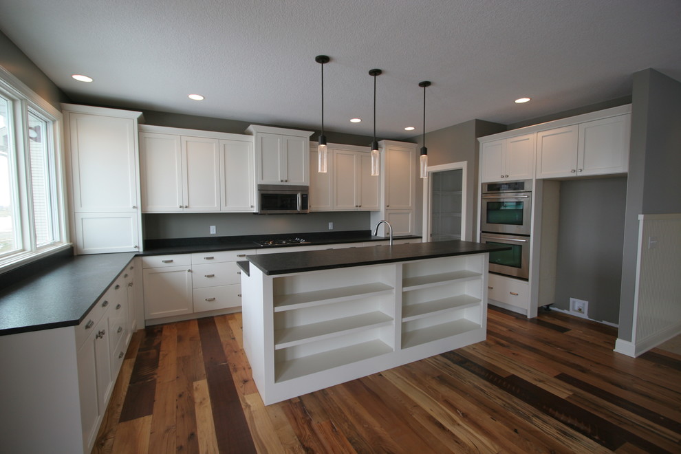 Mid-sized transitional u-shaped eat-in kitchen in Chicago with an undermount sink, recessed-panel cabinets, white cabinets, granite benchtops, white splashback, ceramic splashback, stainless steel appliances, dark hardwood floors and with island.