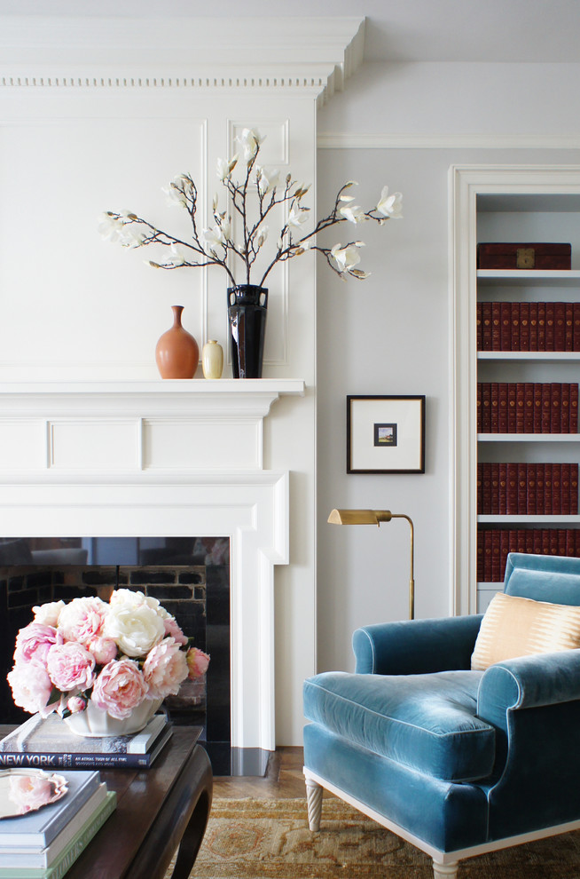 Inspiration for a mid-sized eclectic enclosed living room in New York with a library, light hardwood floors, a standard fireplace, a brick fireplace surround, no tv and grey walls.