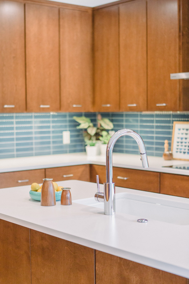 Mid-sized midcentury l-shaped open plan kitchen in Grand Rapids with an undermount sink, flat-panel cabinets, medium wood cabinets, quartz benchtops, blue splashback, ceramic splashback, panelled appliances, light hardwood floors, with island, brown floor and white benchtop.