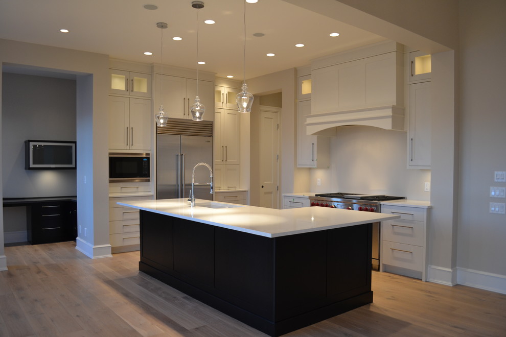 Mid-sized transitional l-shaped light wood floor and beige floor open concept kitchen photo with an undermount sink, recessed-panel cabinets, white cabinets, quartz countertops, white backsplash, stone slab backsplash, stainless steel appliances and an island