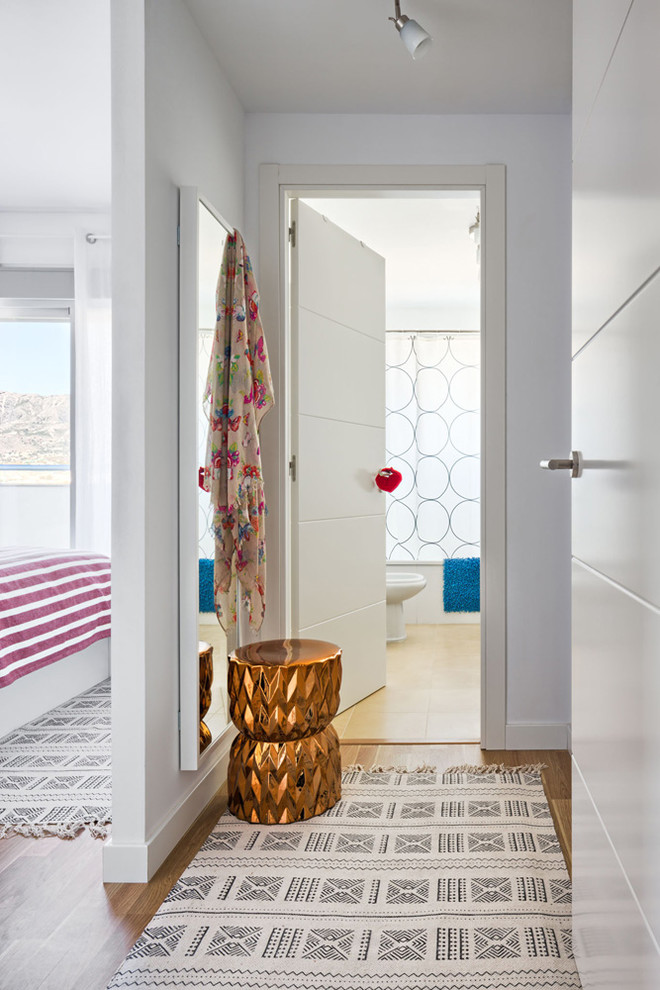 This is an example of a small eclectic hallway in Malaga with white walls and medium hardwood floors.