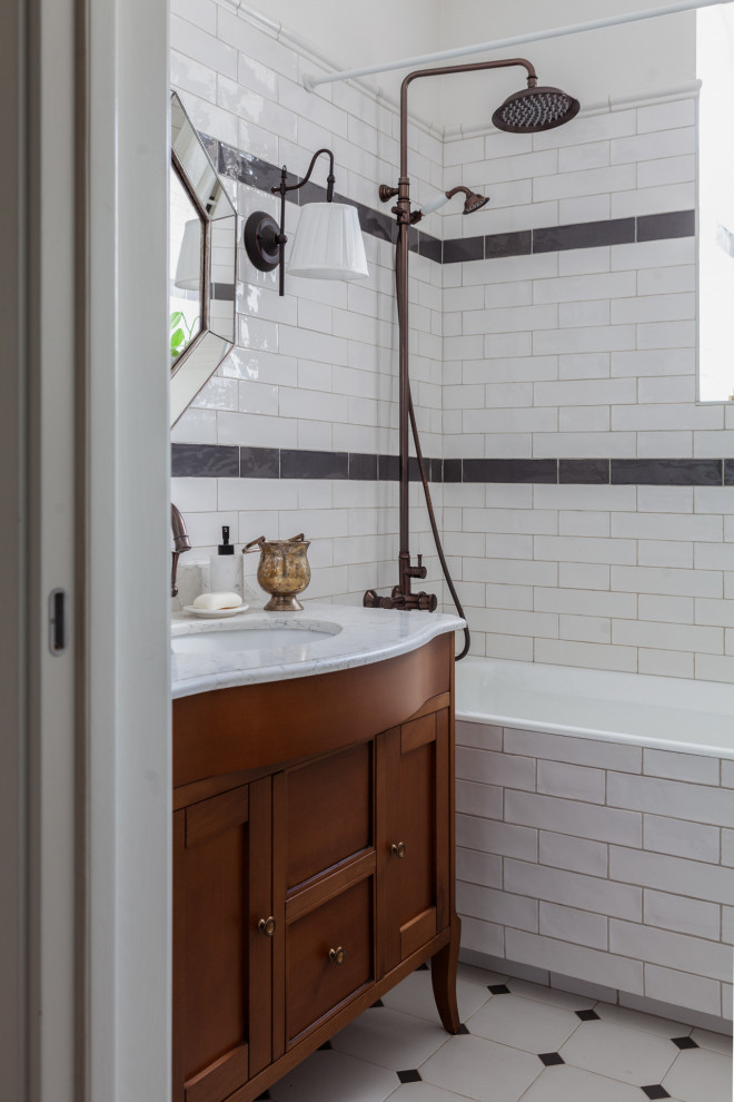 Источник вдохновения для домашнего уюта: маленькая главная, серо-белая ванная комната в классическом стиле с фасадами с выступающей филенкой, темными деревянными фасадами, полновстраиваемой ванной, унитазом-моноблоком, белой плиткой, черно-белой плиткой, черной плиткой, плиткой кабанчик, белыми стенами, полом из керамогранита, настольной раковиной, мраморной столешницей, белым полом, белой столешницей, окном, тумбой под одну раковину и напольной тумбой для на участке и в саду