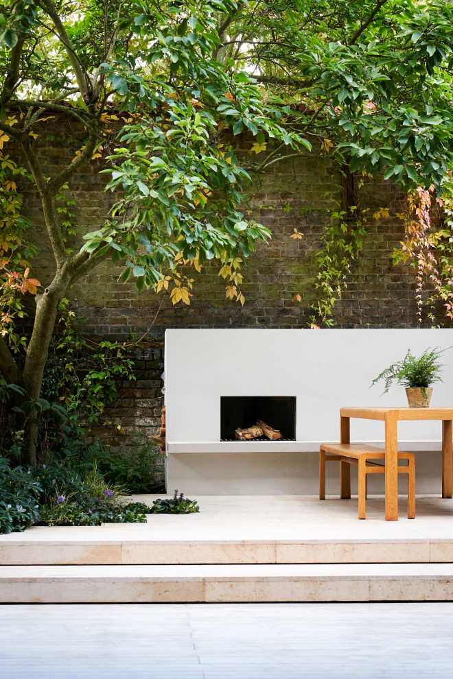 Photo of a small contemporary backyard patio in London with with fireplace and decking.