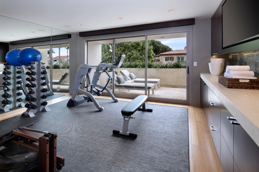 This is an example of a contemporary multipurpose gym in Orange County with grey walls and light hardwood floors.