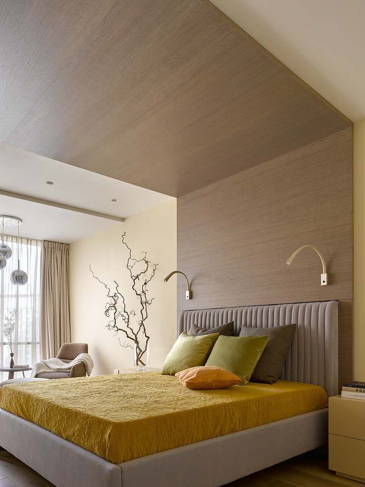 This is an example of a contemporary master bedroom in Moscow with beige walls and light hardwood floors.