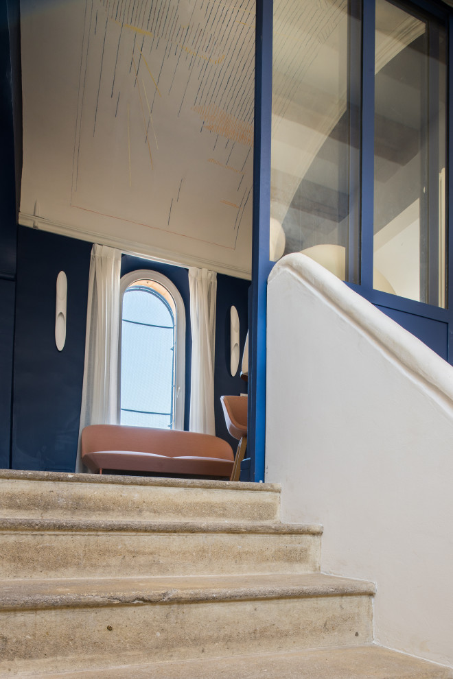マルセイユにある高級なコンテンポラリースタイルのおしゃれな玄関ラウンジ (青い壁、ライムストーンの床、ベージュの床、三角天井) の写真