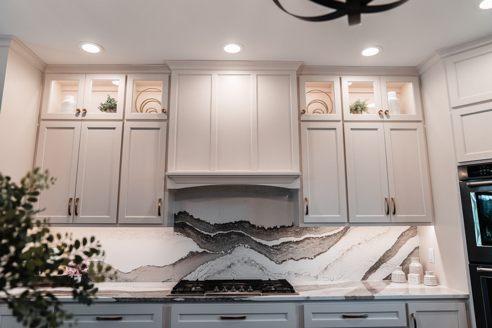 Inspiration for a large transitional l-shaped medium tone wood floor and brown floor open concept kitchen remodel with an undermount sink, flat-panel cabinets, white cabinets, quartz countertops, multicolored backsplash, quartz backsplash, black appliances, an island and multicolored countertops