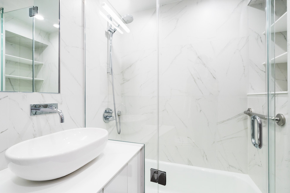 Design ideas for a small modern bathroom in New York with flat-panel cabinets, white cabinets, an alcove tub, white tile, porcelain tile, white walls, porcelain floors, a vessel sink and solid surface benchtops.