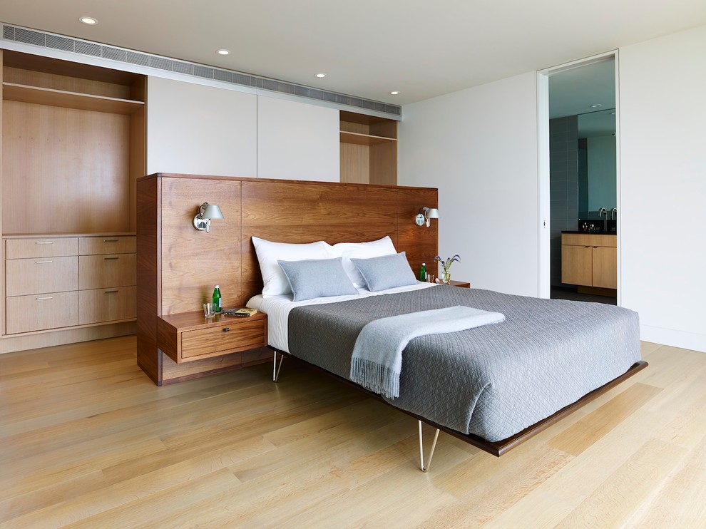 Modern master bedroom in New York with white walls and light hardwood floors.